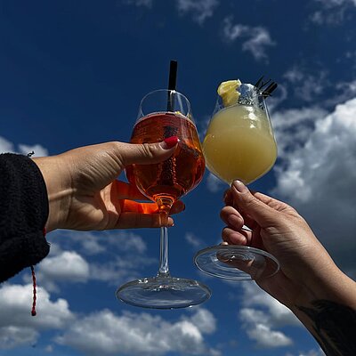 Zwei Spritz-Gläser, angestossen vor blauem Himmel